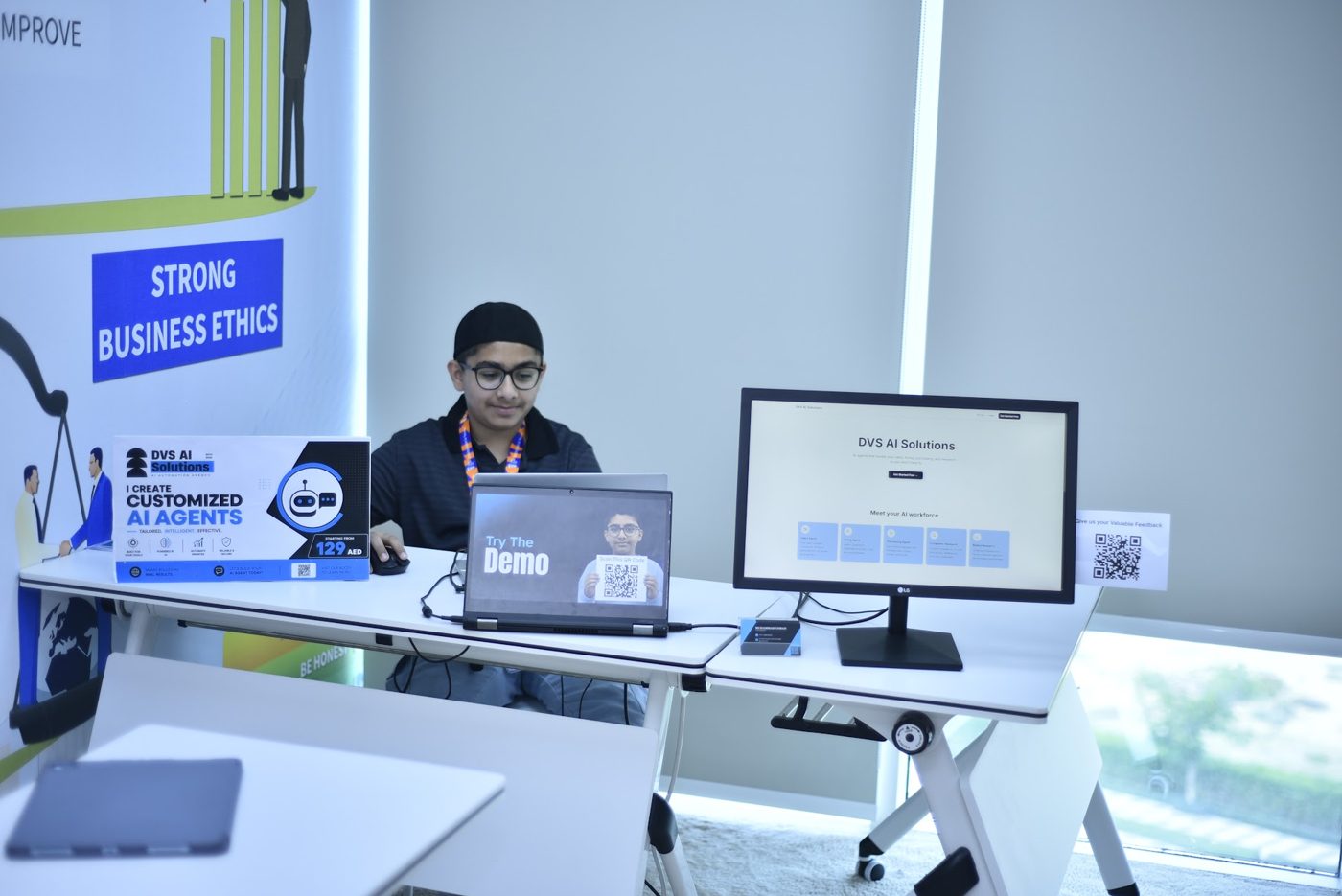 Student presenting his AI agent booth project with a laptop and demo screen